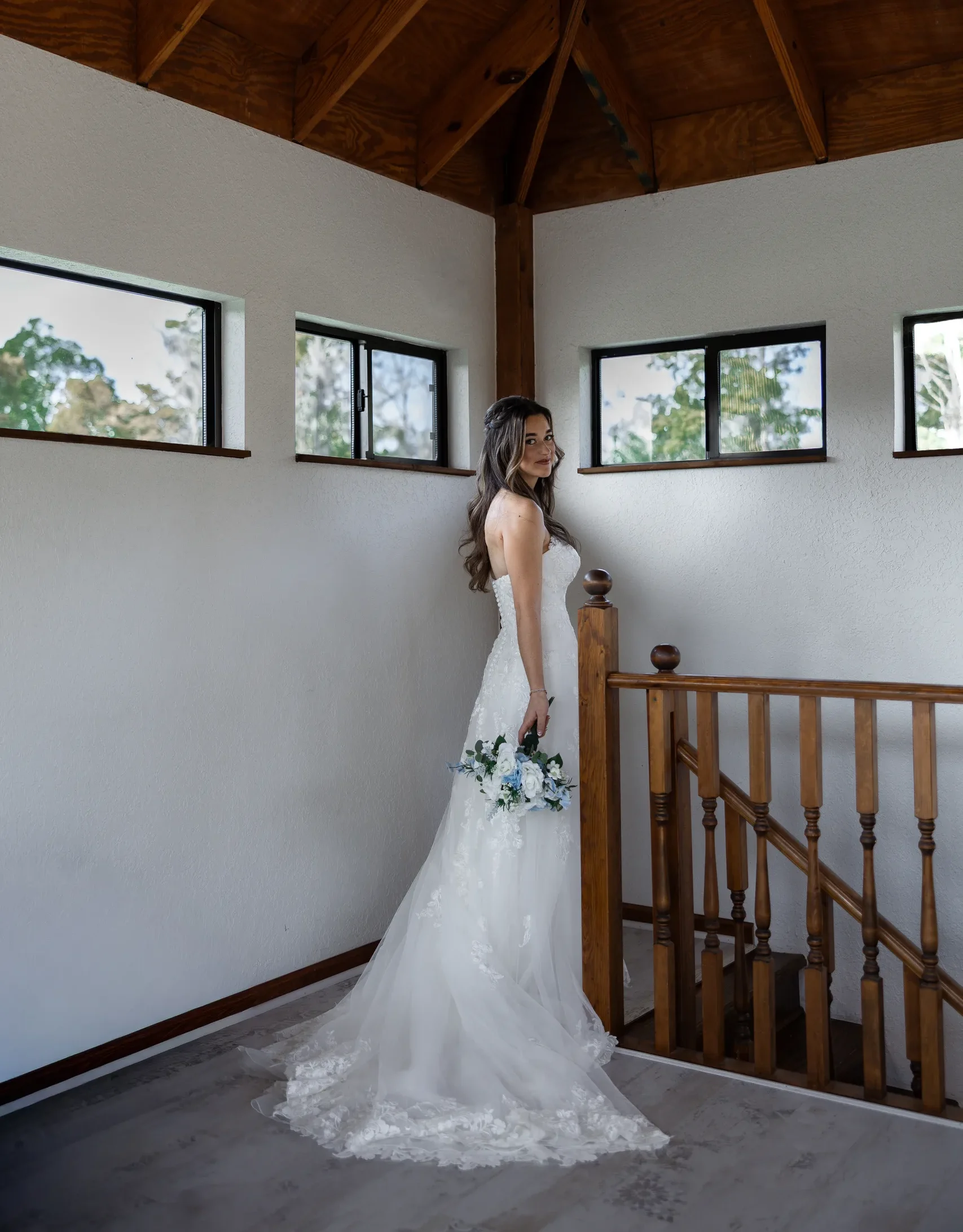 Bride at the top of the wooden staircase under the vaulted farmhouse ceiling at Cypress Creek Farmhouse, Orlando FL