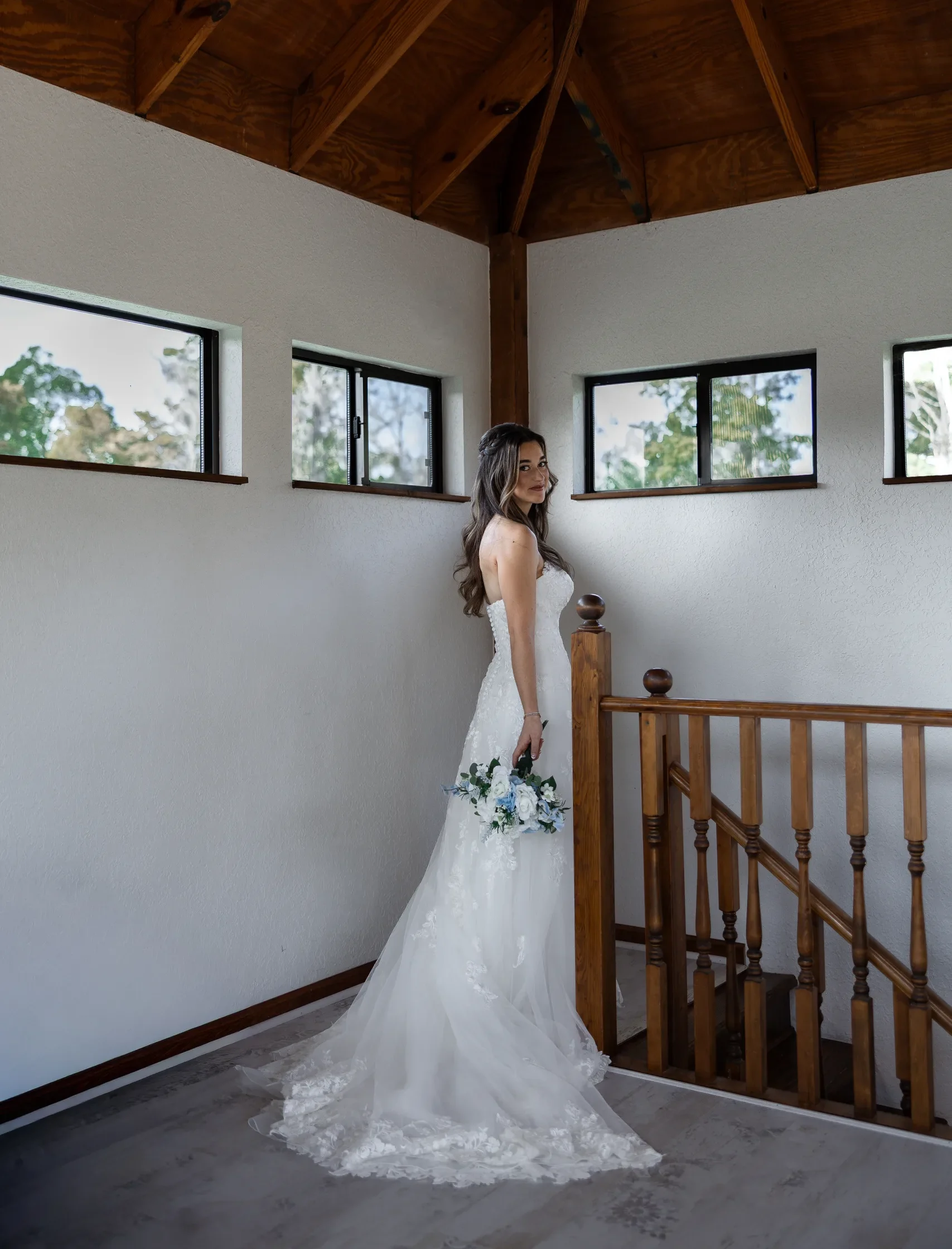 Bride at the top of the wooden staircase under the vaulted farmhouse ceiling at Cypress Creek Farmhouse, Orlando FL