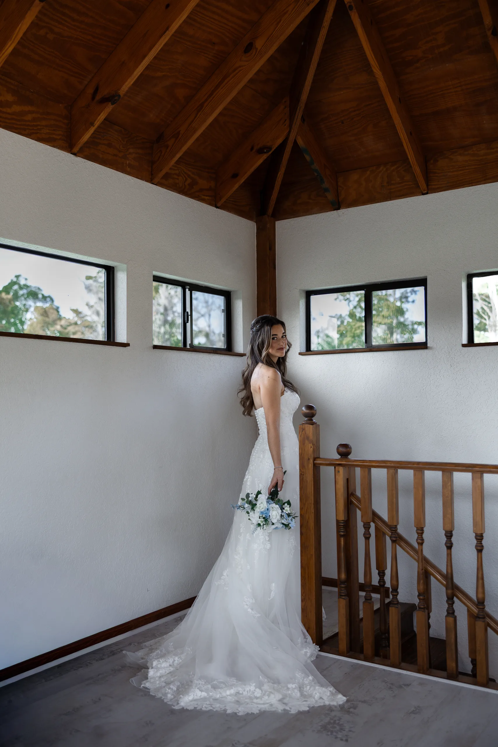 Bride at the top of the wooden staircase under the vaulted farmhouse ceiling at Cypress Creek Farmhouse, Orlando FL