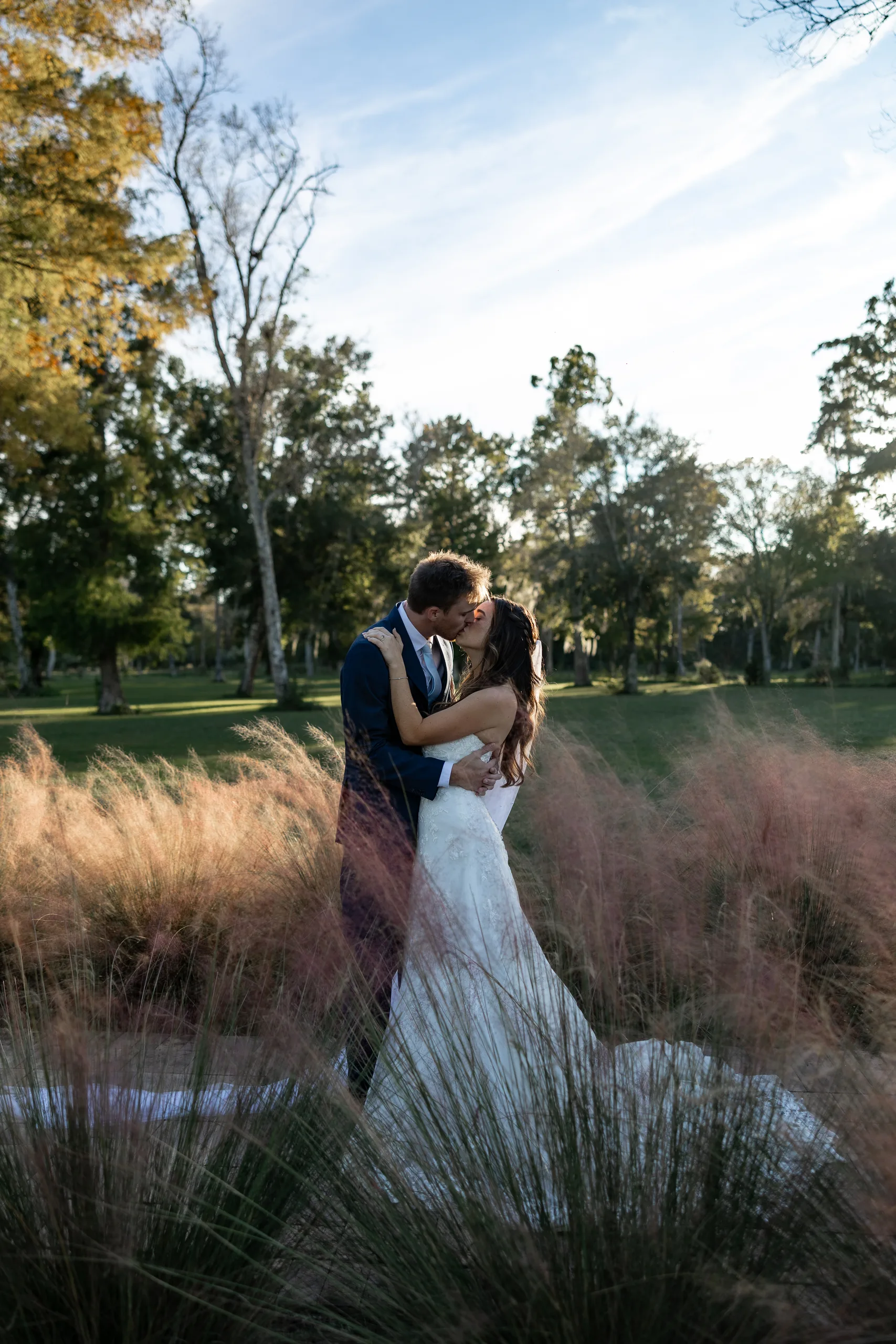 Bride and groom kissing in the pink muhly grass at Cypress Creek Farmhouse, Orlando FL