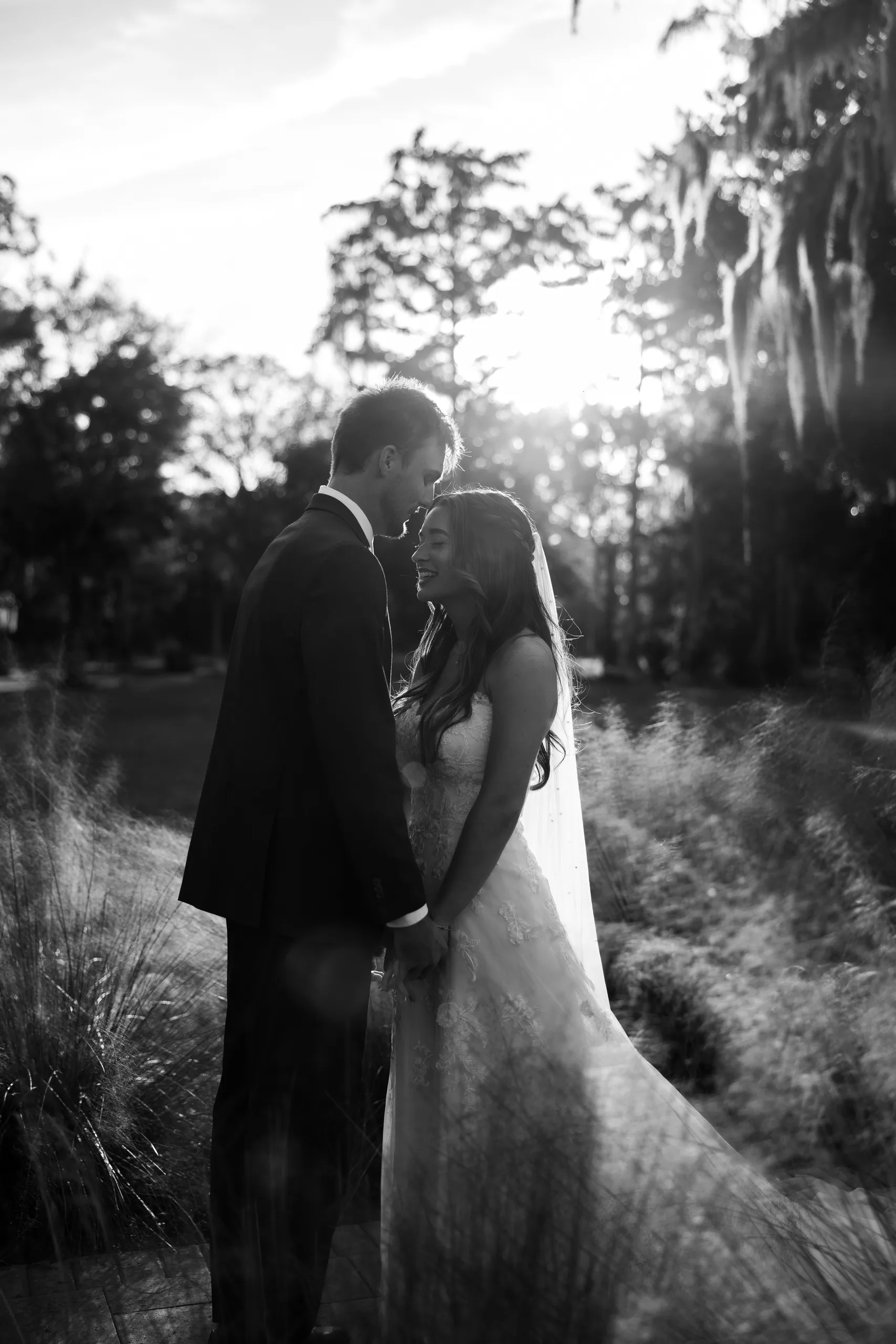 Bride and groom forehead to forehead in the tall grass at golden hour at Cypress Creek Farmhouse, Orlando FL
