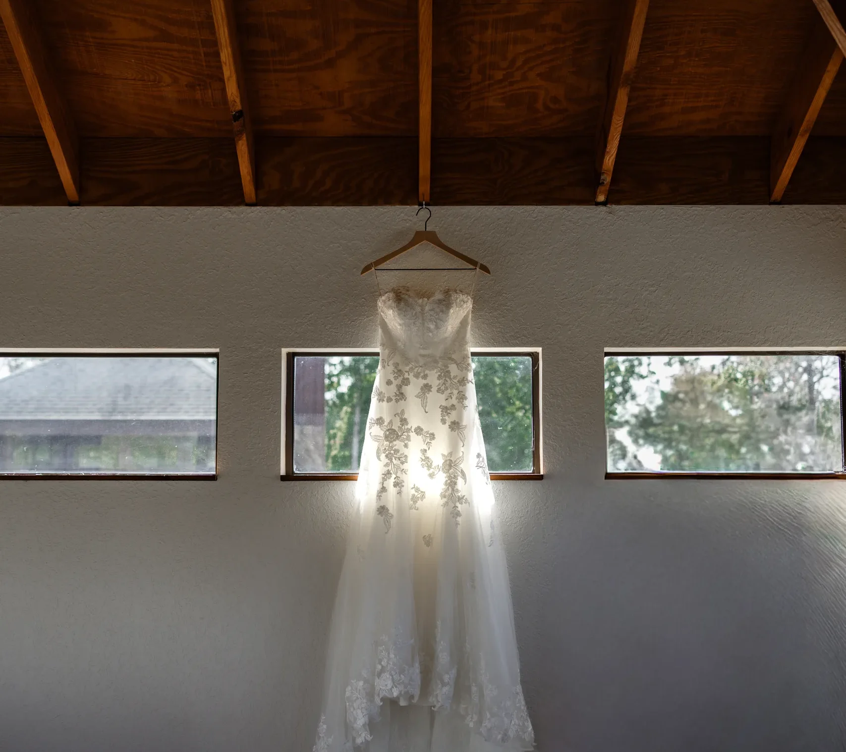 Wedding dress hanging from the exposed wood beams of the farmhouse at Cypress Creek Farmhouse, Orlando FL