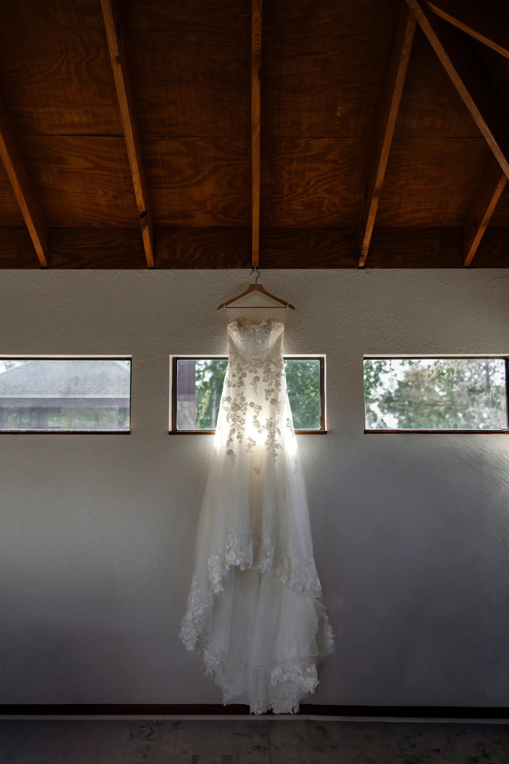 Wedding dress hanging from the exposed wood beams of the farmhouse at Cypress Creek Farmhouse, Orlando FL