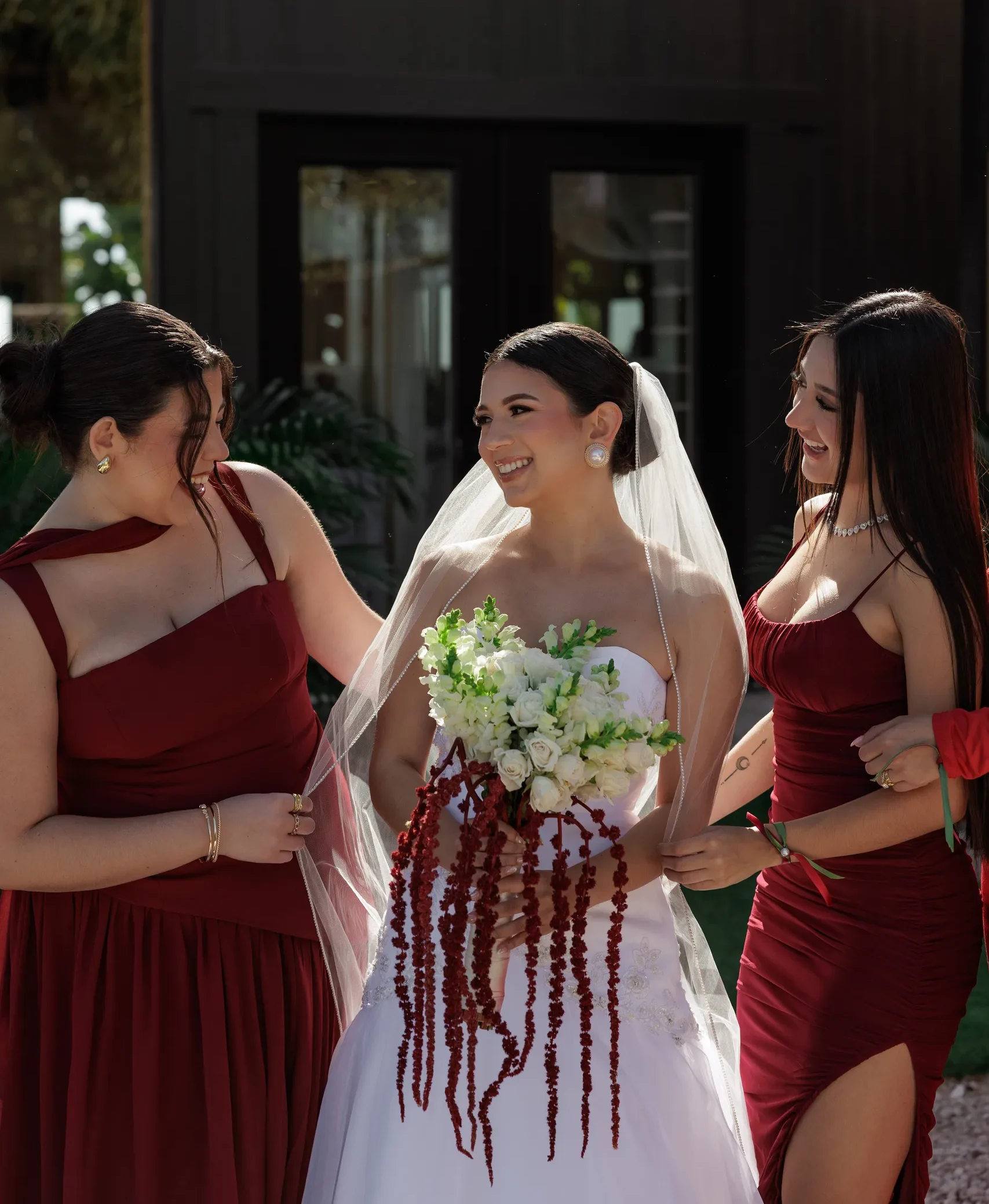 Bride and bridesmaids in dark red dresses outside the black barn at The Hill House, Clermont FL