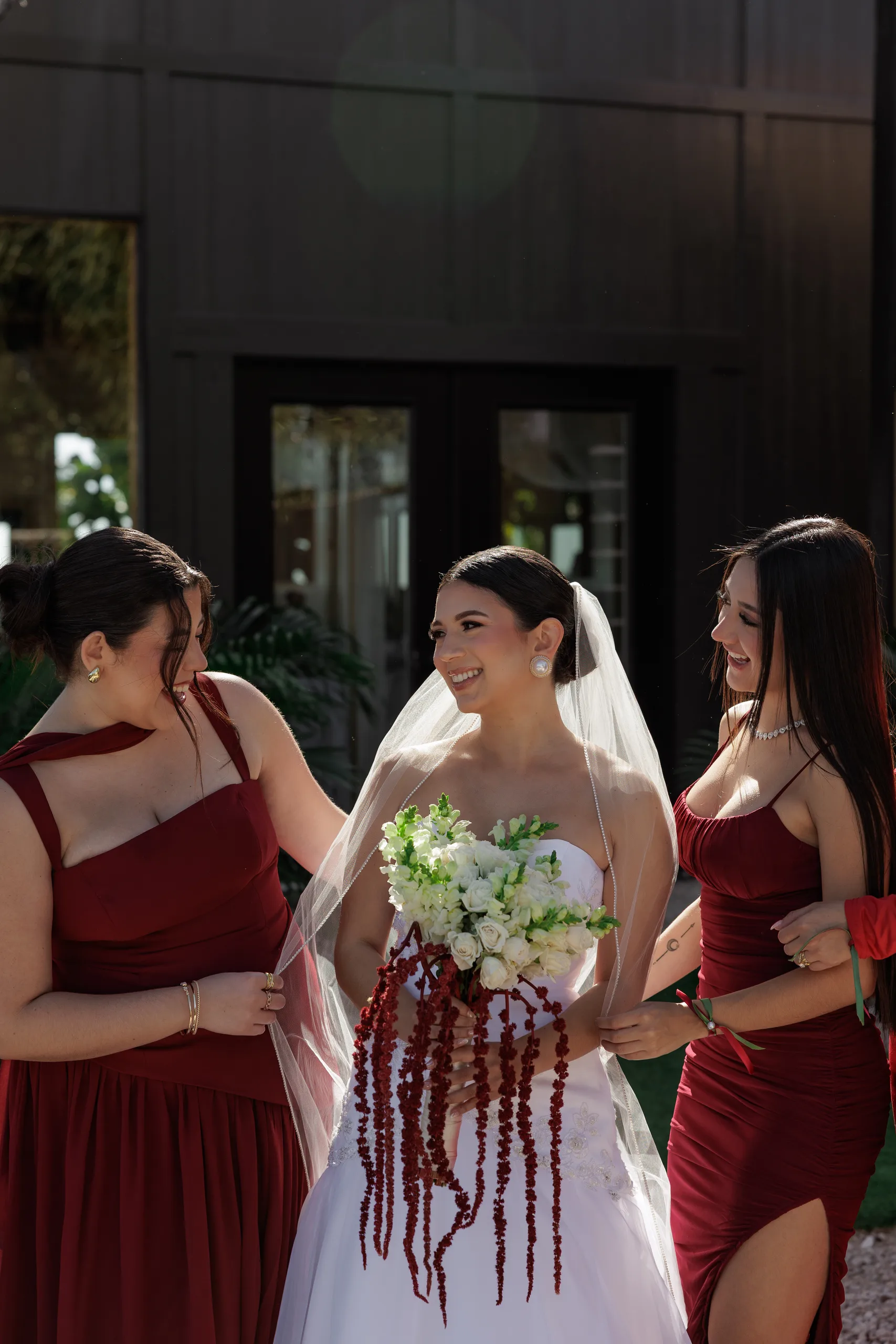Bride and bridesmaids in dark red dresses outside the black barn at The Hill House, Clermont FL