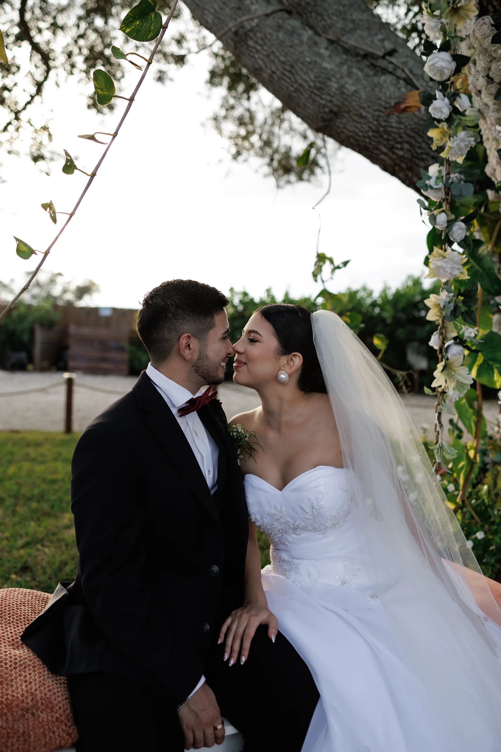 Bride and groom nose to nose on the flower-wrapped oak tree swing at The Hill House, Clermont FL