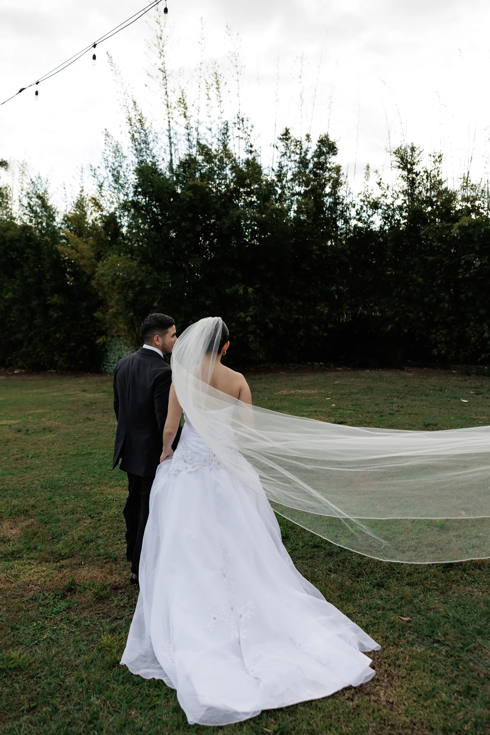 Newlyweds walking the lawn with the bride's veil trailing at The Hill House, Clermont FL