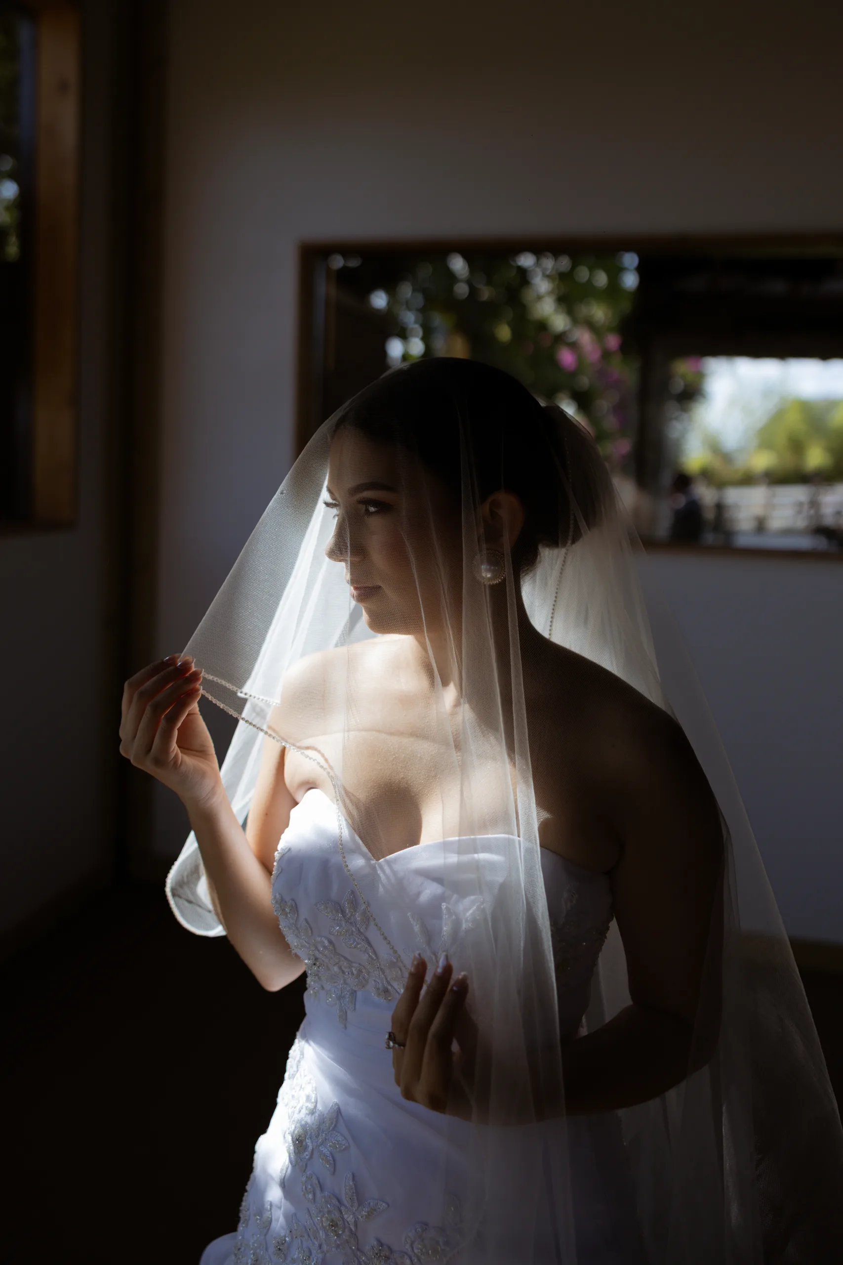 Bride under her veil in window light while getting ready at The Hill House, Clermont FL