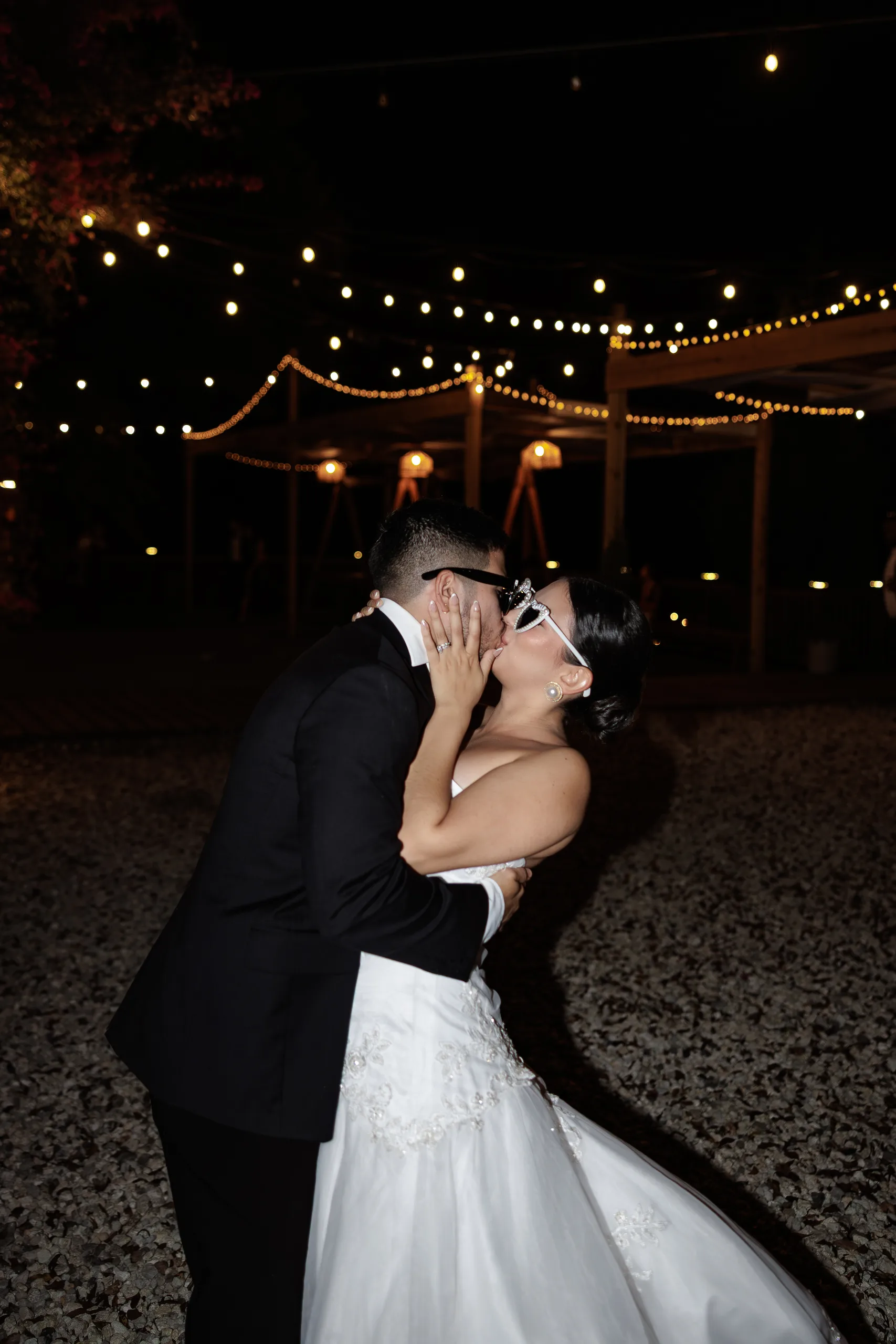 Bride and groom kiss under string lights at The Hill House, Clermont FL
