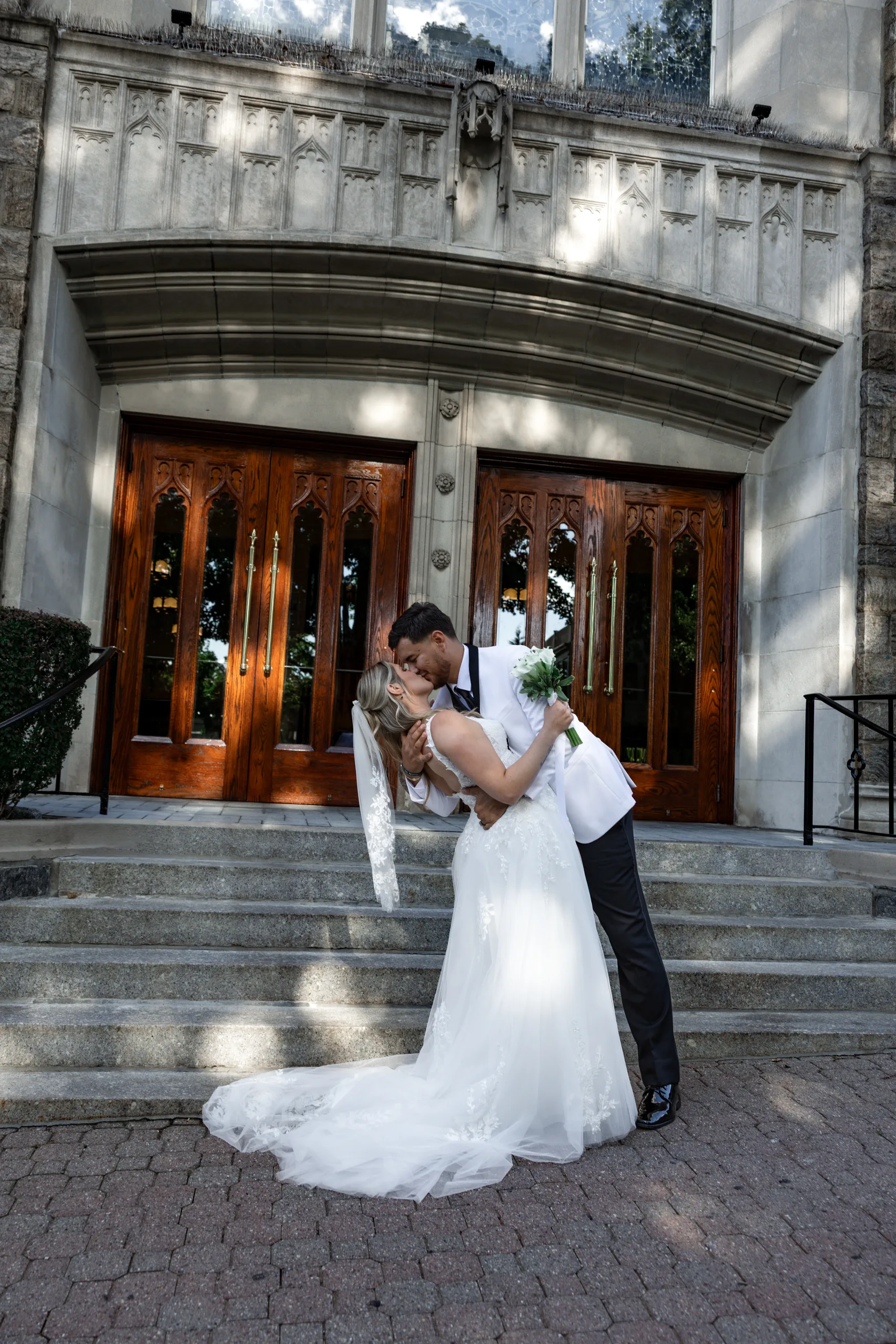 Just-married dip kiss on the stone church steps in Bronxville, NY, before The J House Greenwich reception