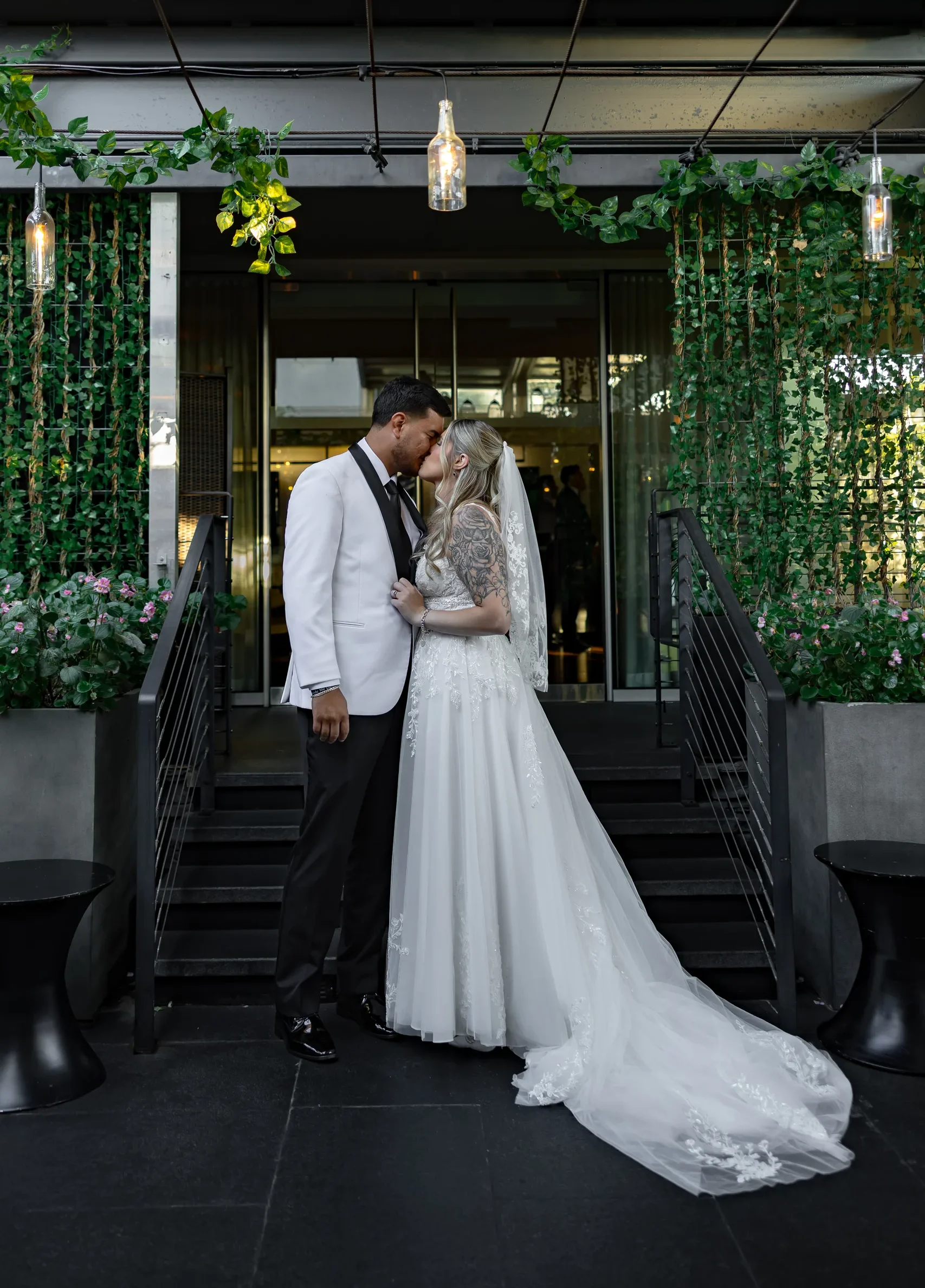 Bride and groom kissing under the hanging greenery at The J House Greenwich entrance, Greenwich CT