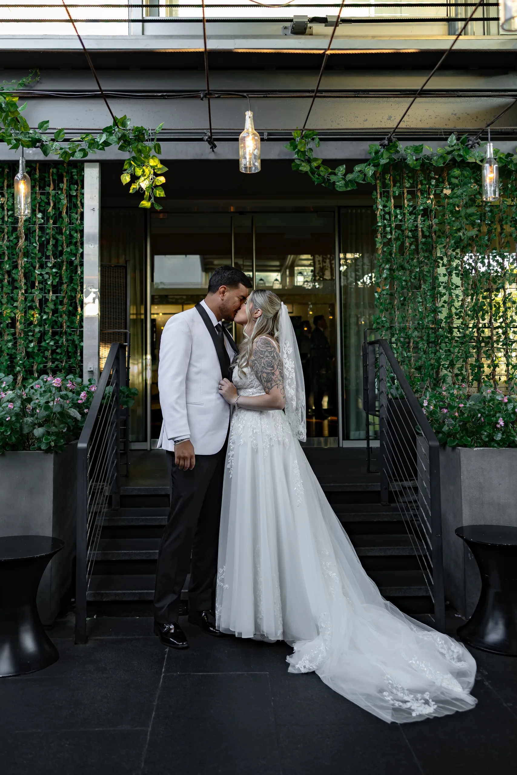 Bride and groom kissing under the hanging greenery at The J House Greenwich entrance, Greenwich CT