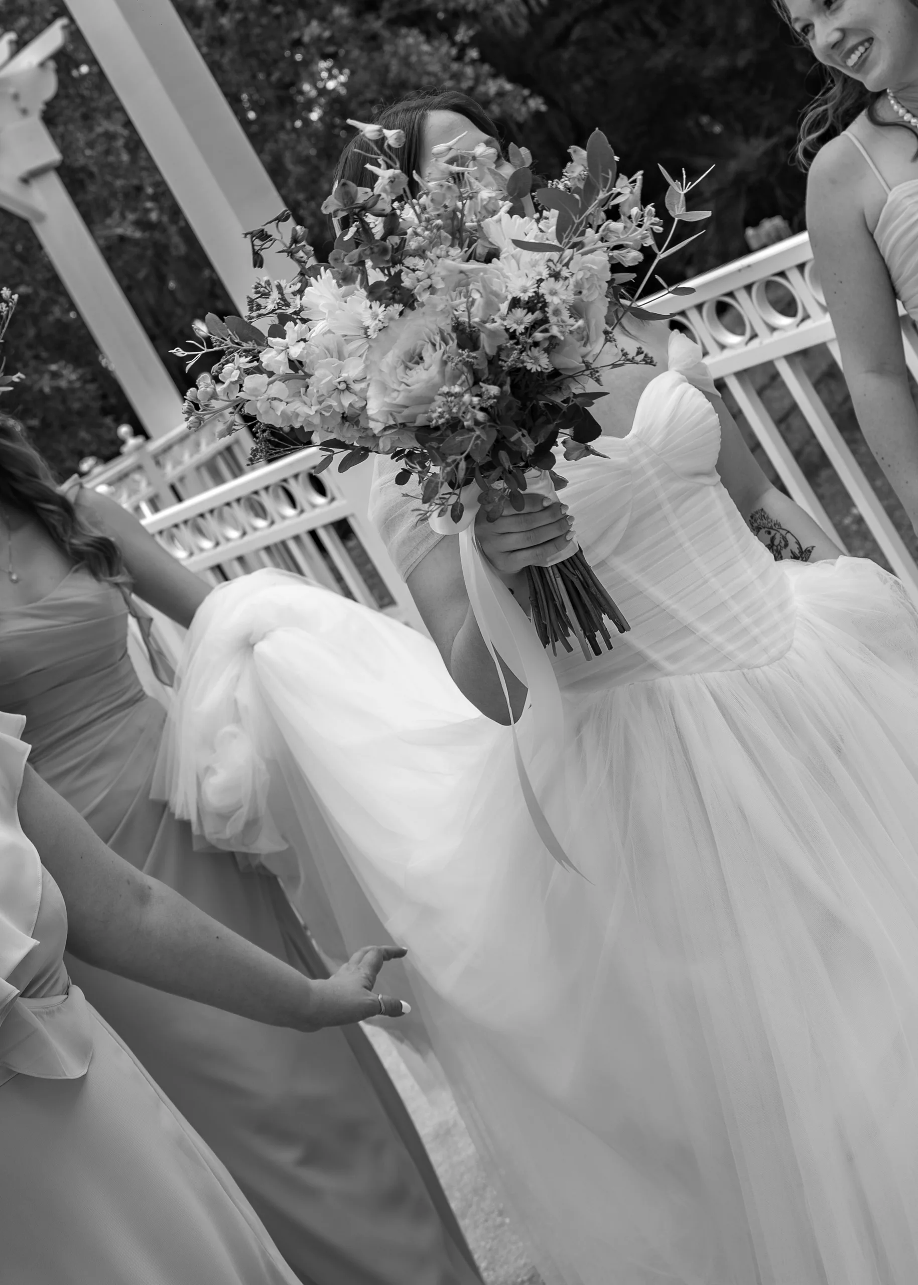 Bride holding her bouquet up while a bridesmaid arranges her train at Lake Mary Events Center