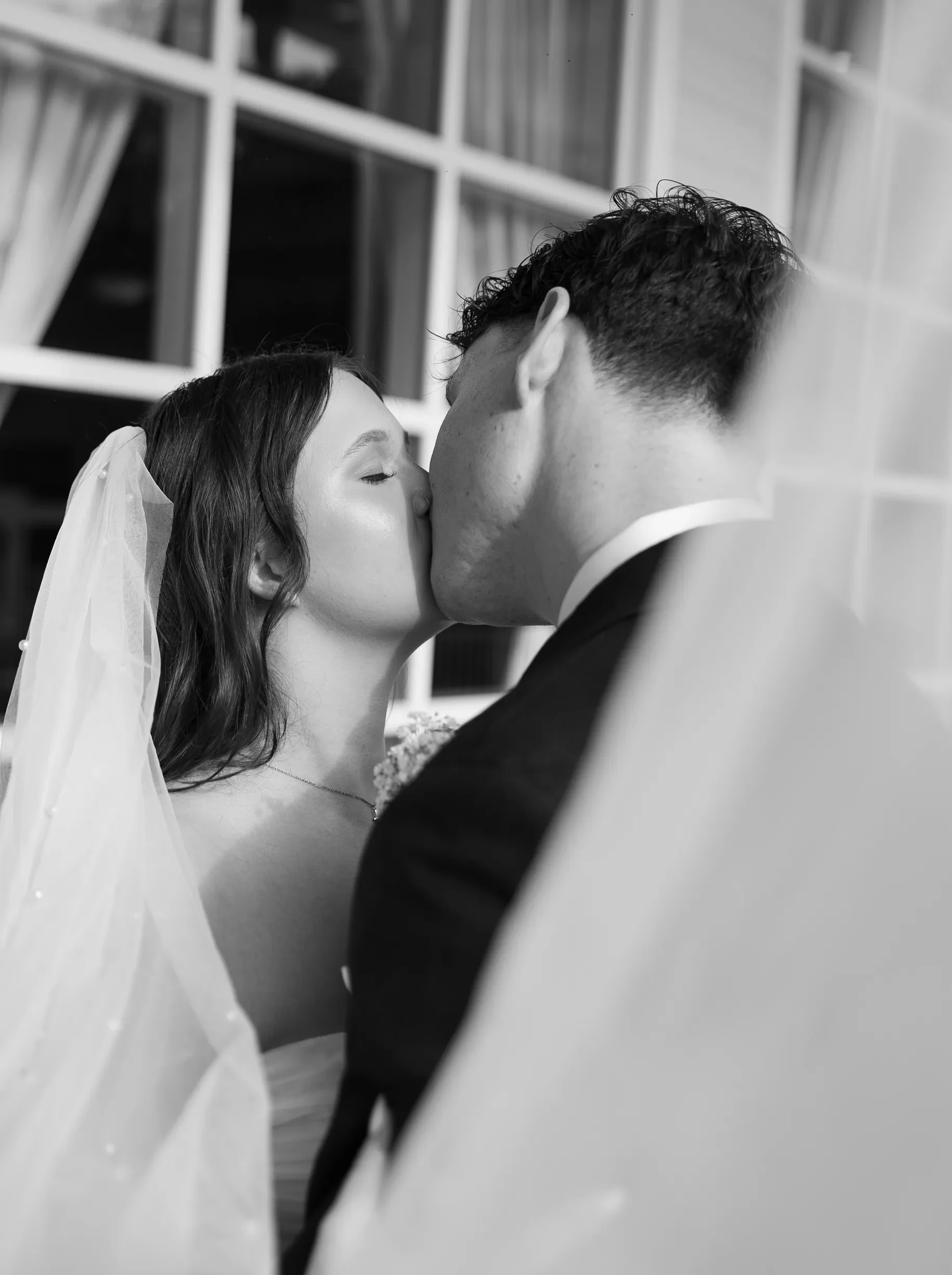 Bride and groom share a kiss by the window at Lake Mary Events Center