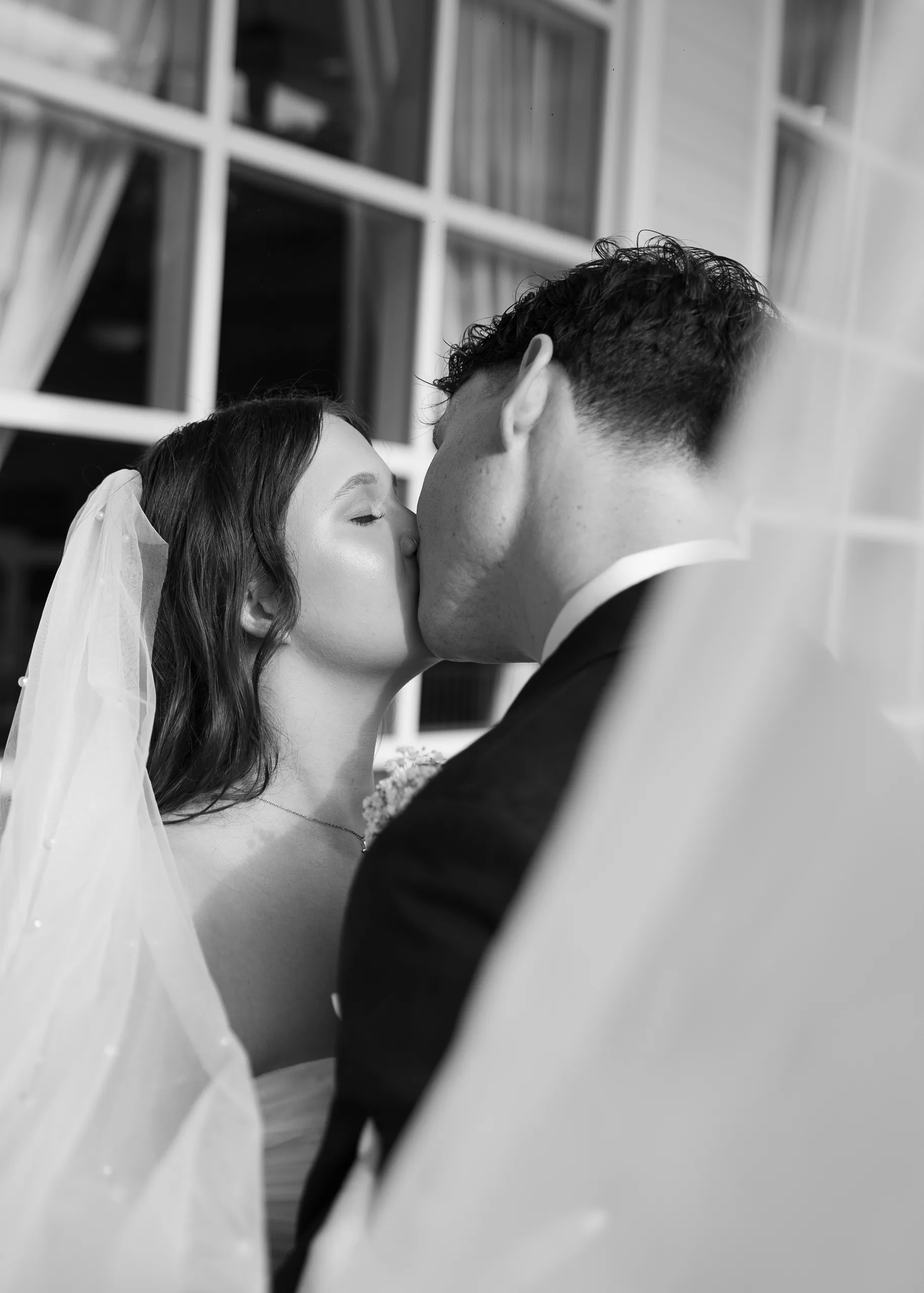 Bride and groom share a kiss by the window at Lake Mary Events Center