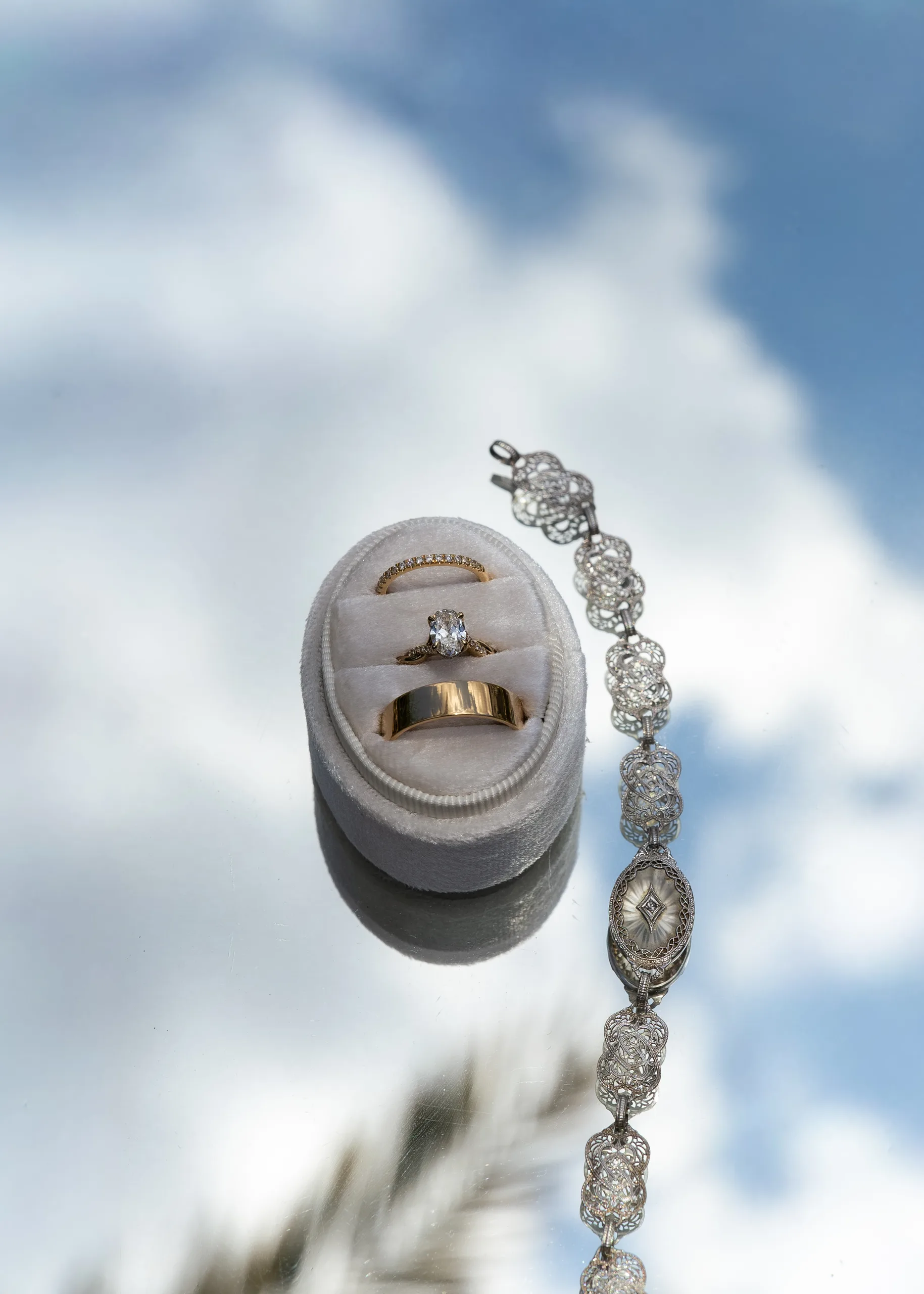 Wedding rings and bracelet reflected against the sky at Lake Mary Events Center