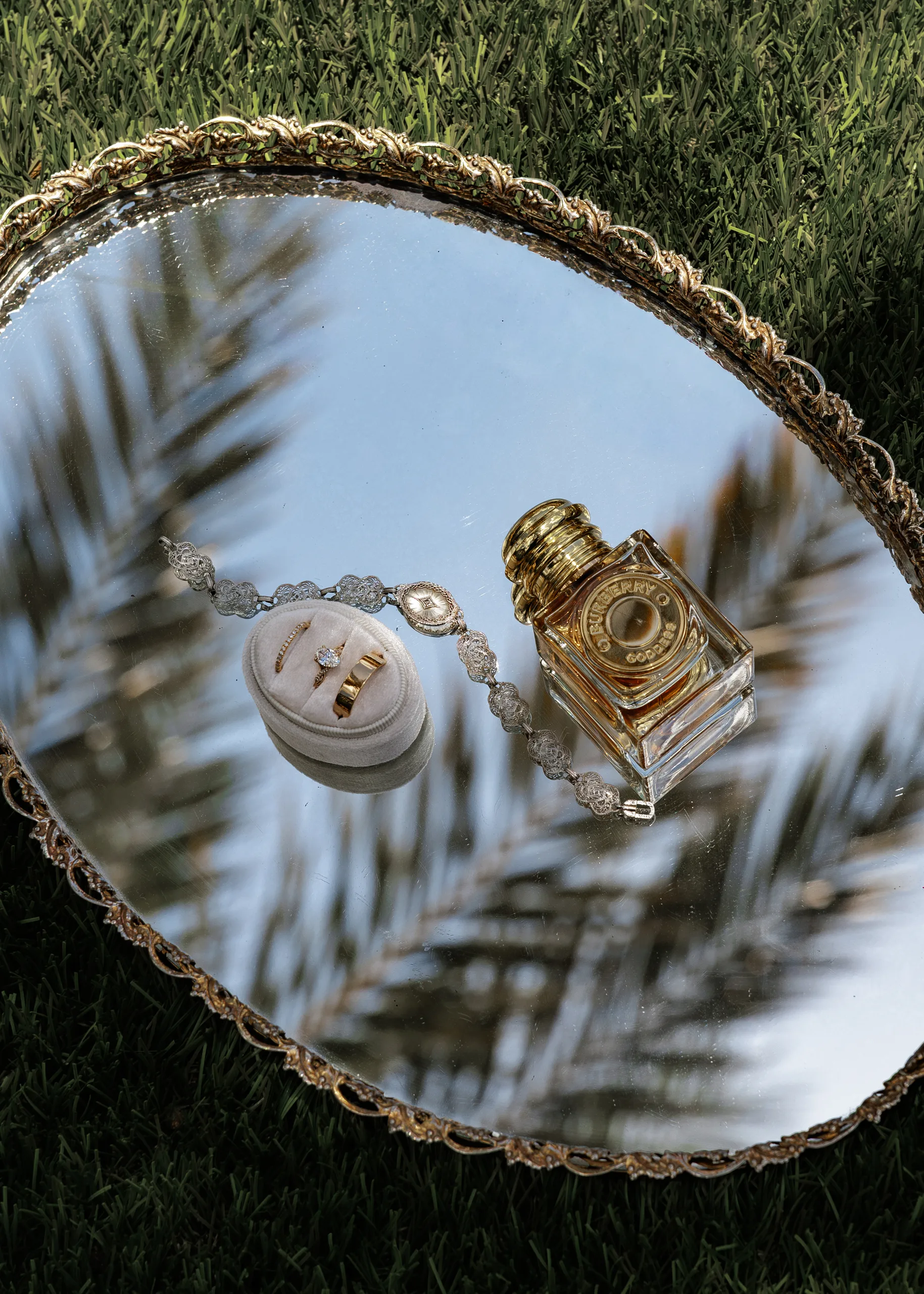 Bride's rings, bracelet, and perfume on a mirrored tray before a wedding at Lake Mary Events Center