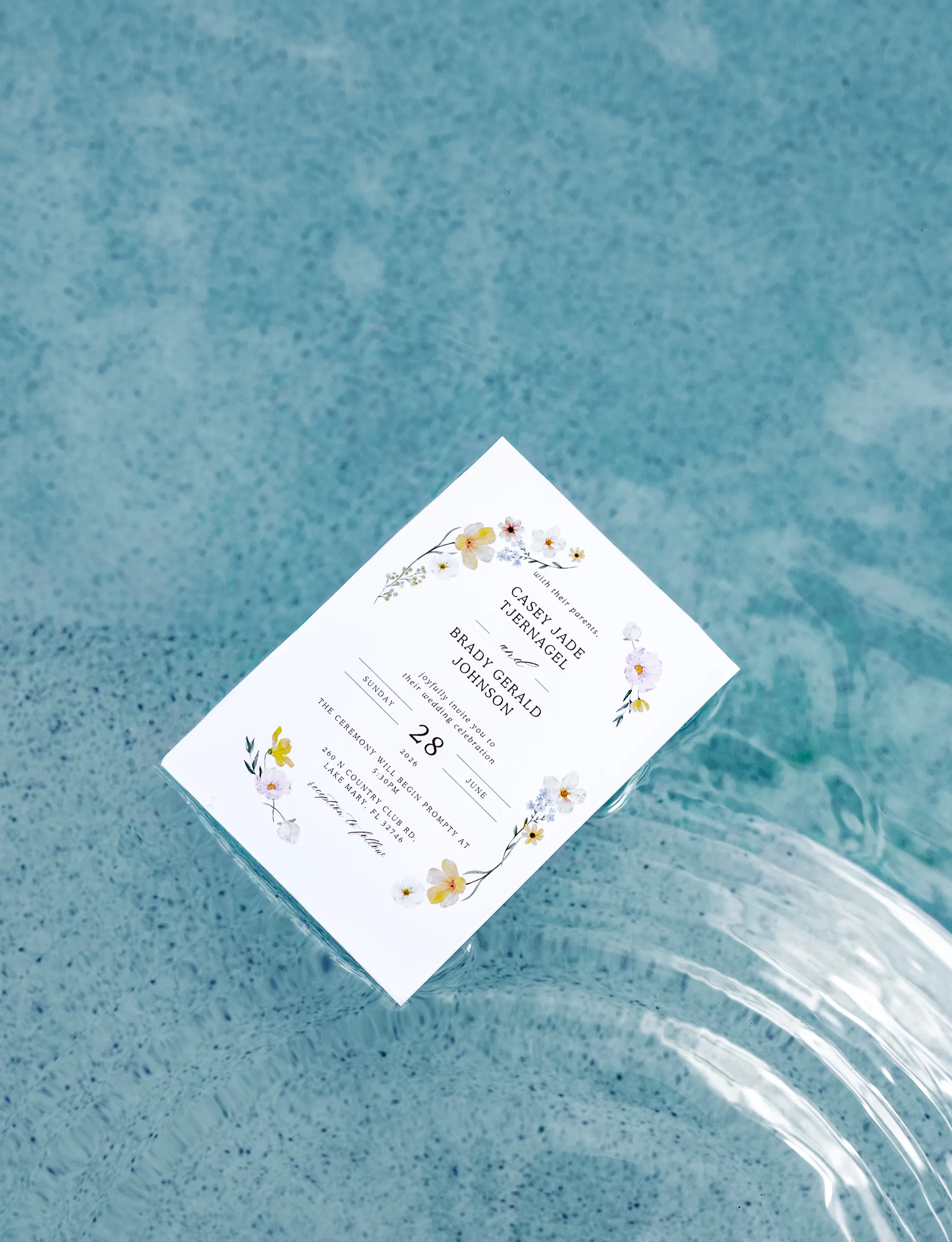 Wedding invitation for Casey and Brady floating in the pool at Lake Mary Events Center