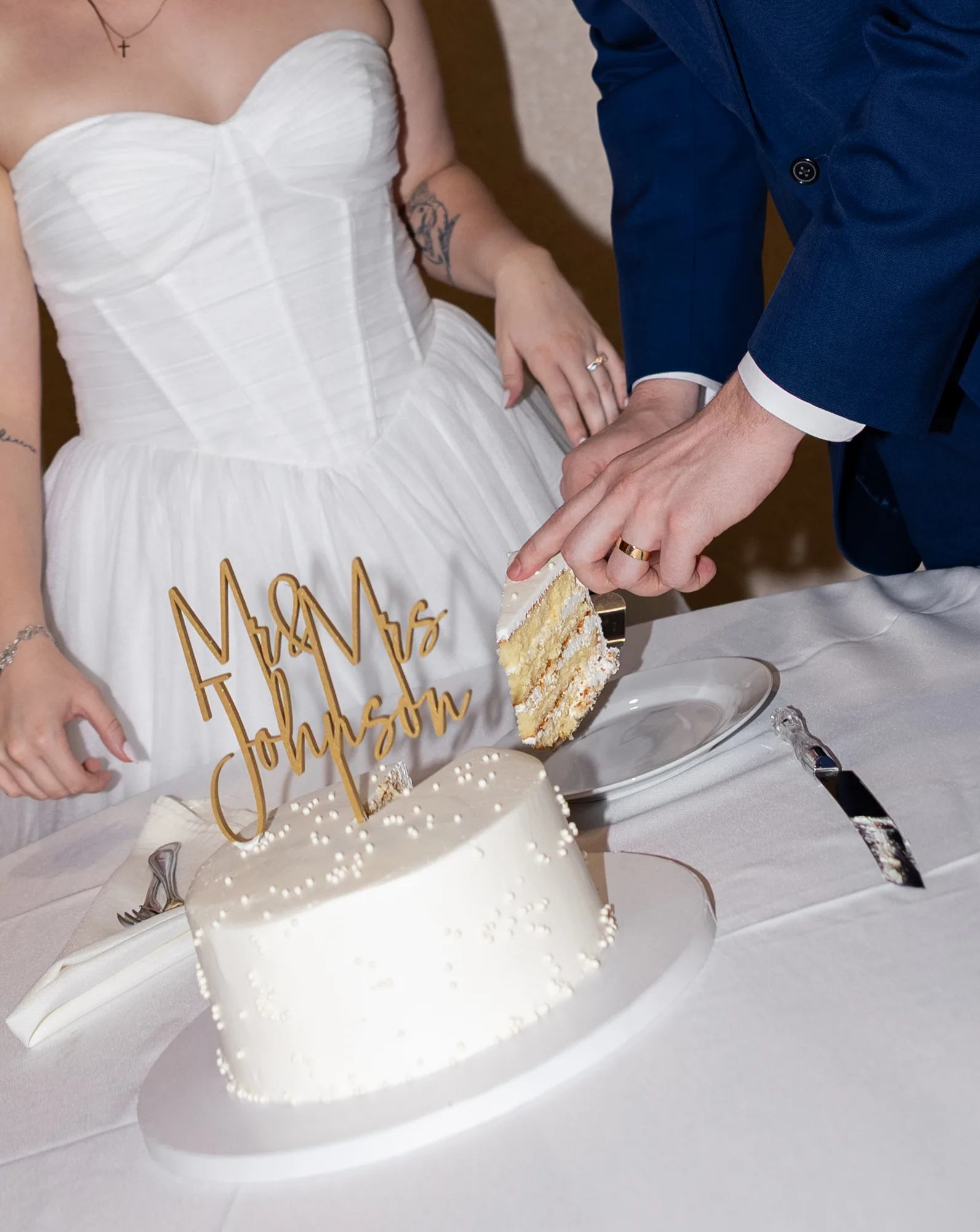 Bride and groom cutting their wedding cake topped with 'Mr & Mrs Johnson' at Lake Mary Events Center