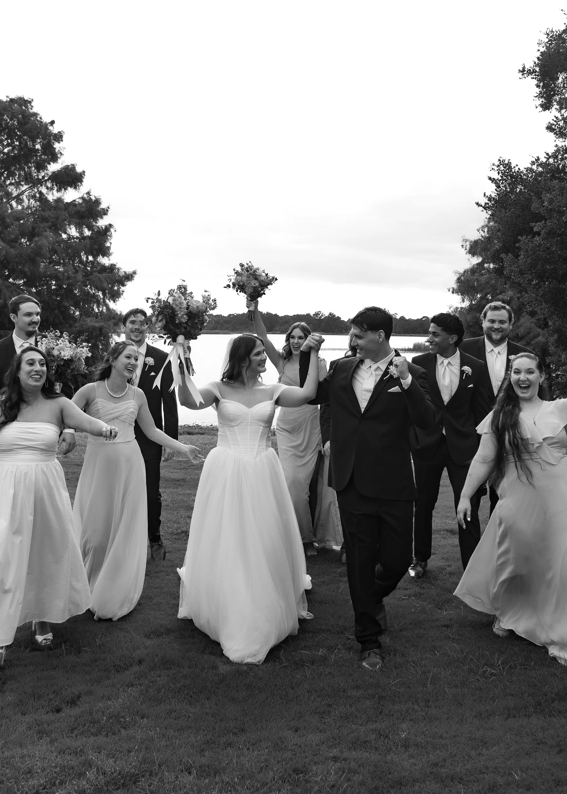 Wedding party running and cheering along the lake at Lake Mary Events Center